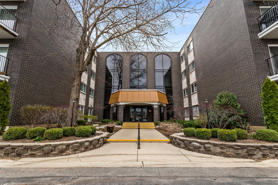 Front view of a multi-story building with a central entrance and large windows.