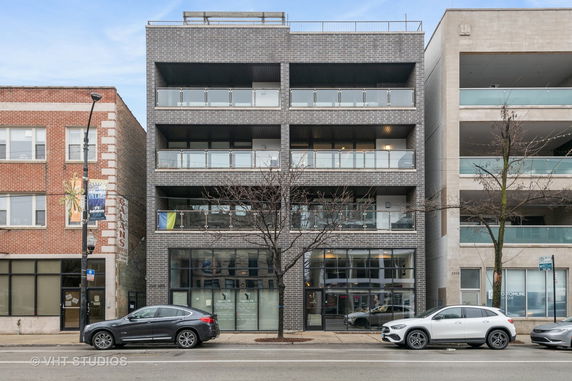 Front view of a multi-story building with balconies and glass railings.