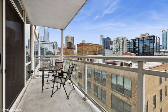 View of surrounding buildings from a balcony with glass railing.