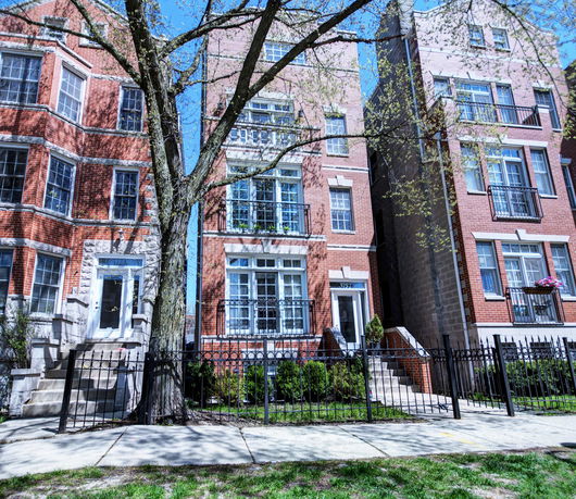 Front view of a multi-story brick building with balconies and a central entrance.