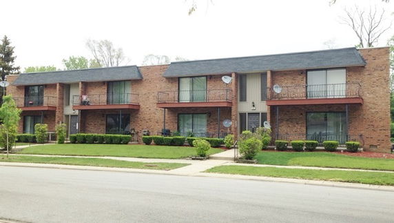 Front view of a two-story brick apartment building with balconies.