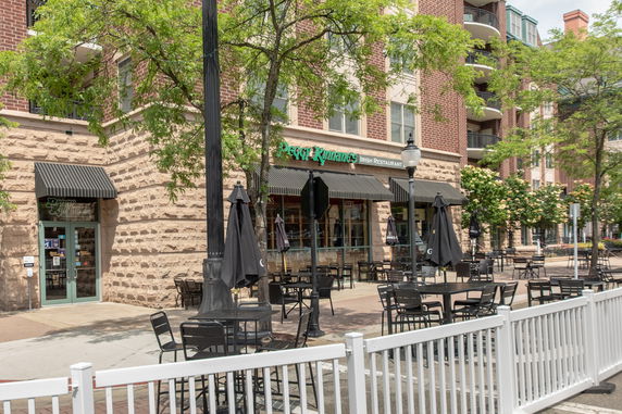 Front view of a restaurant with outdoor seating on a street corner.