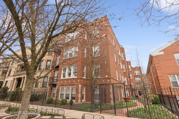 Front view of a multi-story brick building with fenced entrance.