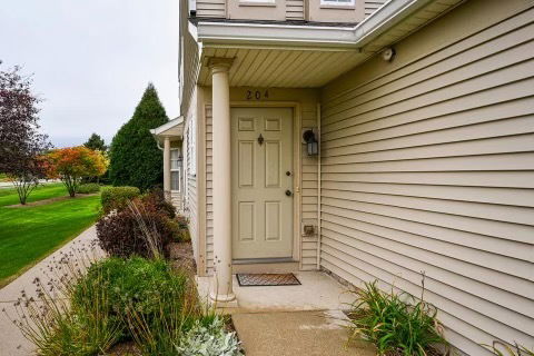 Front entrance of a house with siding and a column next to the door.