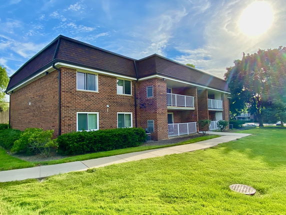 Front view of a two-story brick building with balconies and white railings.