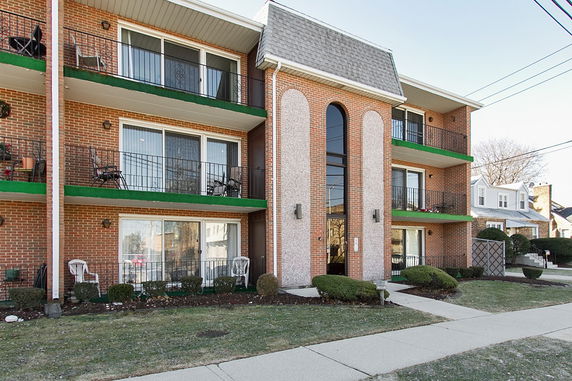 Front view of a multi-story brick apartment building with balconies.
