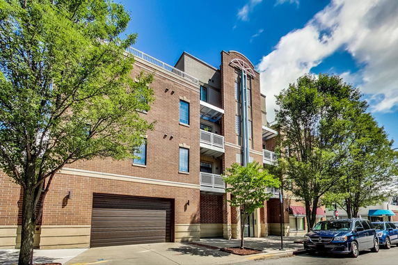 Front view of a multi-story brick building with balconies and a garage entrance.
