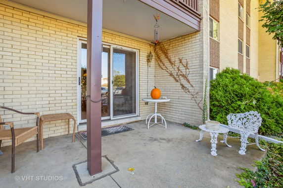 Front view of a brick building with a small patio area featuring outdoor furniture and a table with a pumpkin.