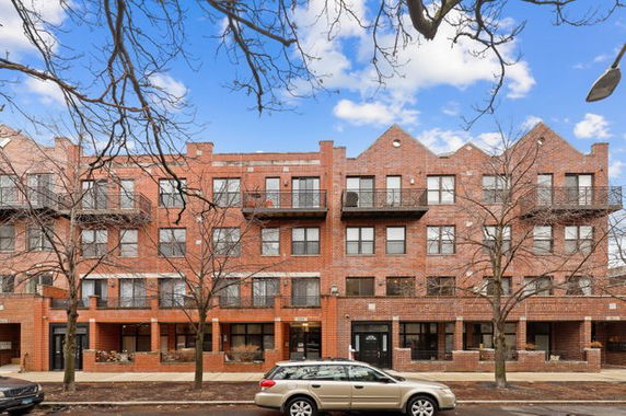 Front view of a multi-story brick apartment building with balconies.