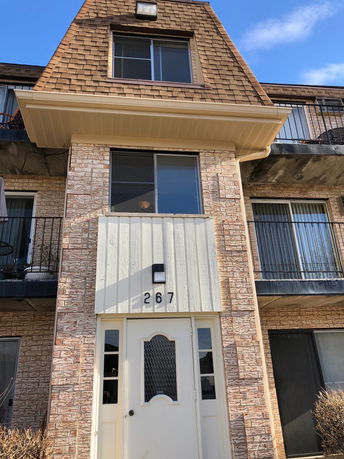 Front view of a multi-story building with brick facade and sliding windows.
