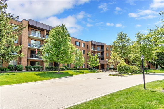 Front view of a multi-story brick apartment building with balconies.