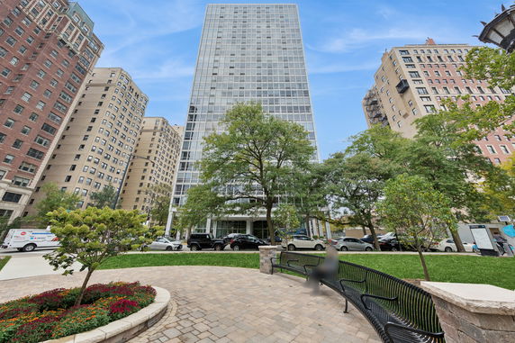 Front view of a tall modern building with glass facade, surrounded by other tall buildings.