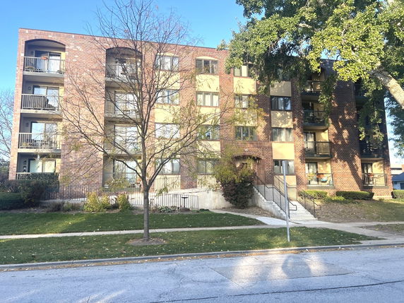 Front view of a multi-story apartment building with brick exterior and balconies.