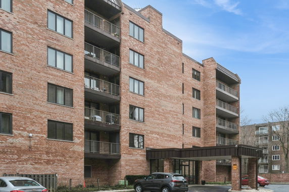 Front view of a multi-story brick apartment building with balconies.