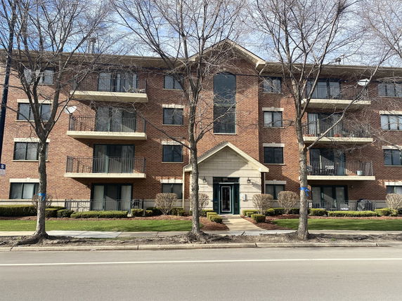 Front view of a four-story brick apartment building with balconies.