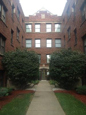 Front view of a multi-story brick apartment building with a central walkway.