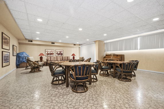 Indoor recreation area with tables and chairs, and a piano.