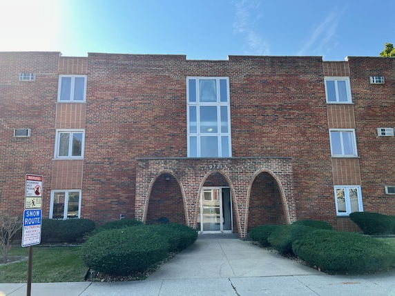 Front view of a multi-story brick building with arched entrance.