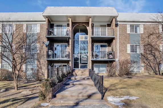 Front view of a multi-story apartment building with balconies and a central entrance.