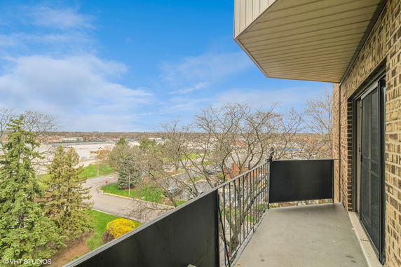 View from a balcony overlooking a suburban area with trees and buildings.