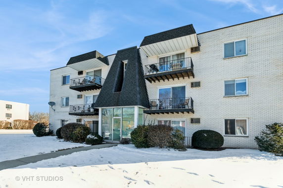Front view of a multi-story brick apartment building with balconies.