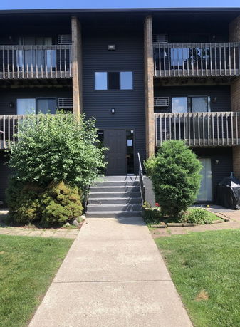 Front view of a multi-story apartment building with balconies and a central entrance.