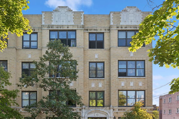 Front view of a four-story brick apartment building with detailed architectural features.