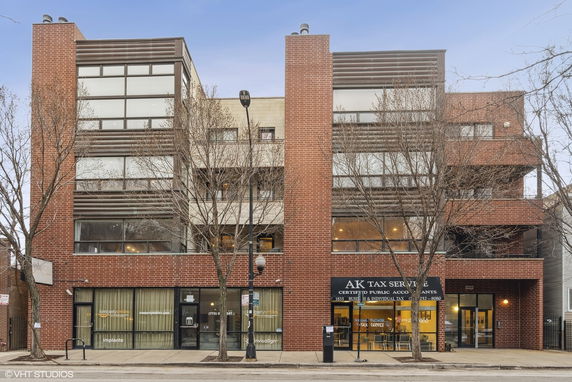 Front elevation of a modern multi-story commercial building with large windows and brick facade.