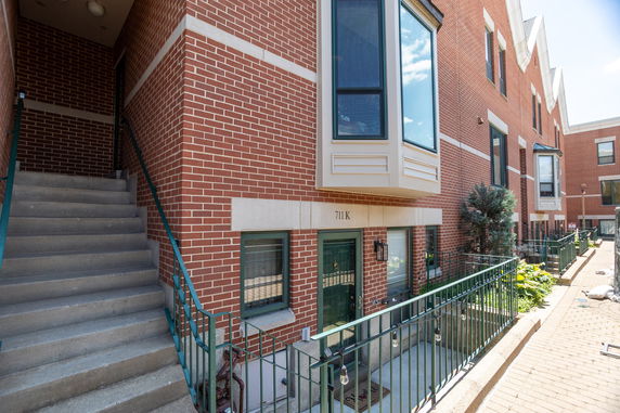 Front view of a multi-story brick townhouse with bay windows and a staircase.
