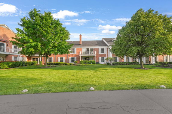 Front view of a two-story brick building with balconies and a well-maintained lawn.