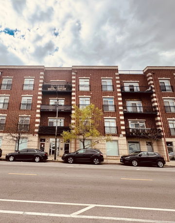 Front view of a three-story brick building with balconies.