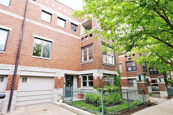 Front view of a multi-story brick townhouse with a garage and fence.