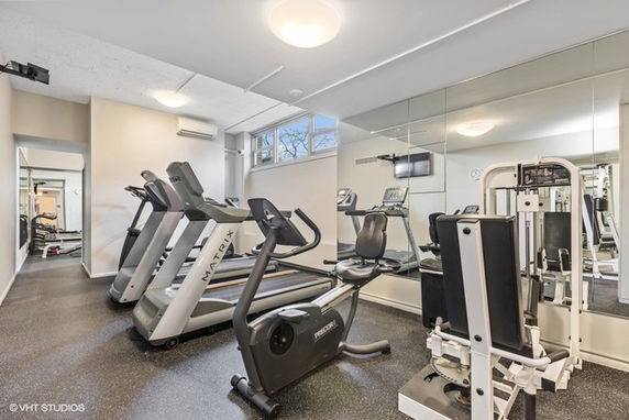 Interior view of a gym with exercise machines and mirrors.