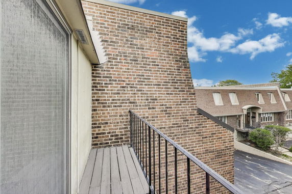 View from a balcony showing nearby brick buildings with distinctive sloped roofs.