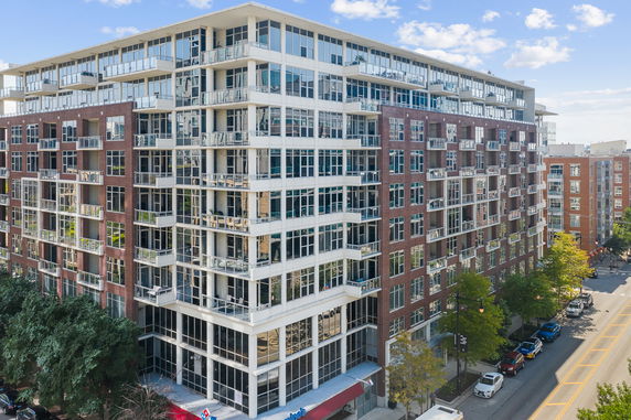 Front view of a multi-story apartment building with large windows and balconies.