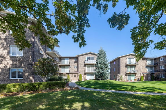 Front view of a multi-story brick apartment complex with balconies.