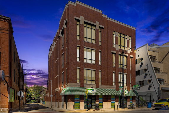 View of a multi-story brick building with large windows and a retail space on the ground floor.