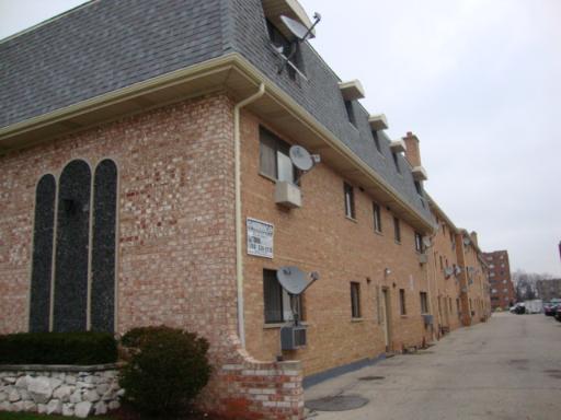 Front view of a brick apartment building with multiple satellite dishes attached.