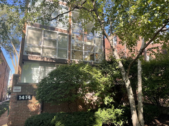 Front view of a multi-story apartment building with large windows and a brick exterior.