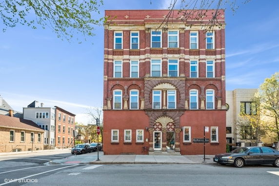 Front view of a multi-story red brick building with decorative elements.
