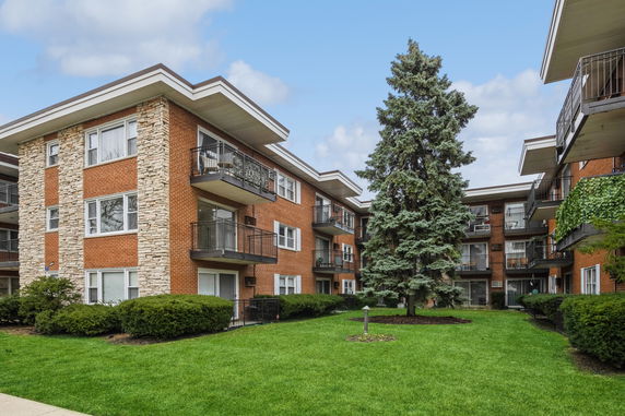 Front view of a multi-story brick apartment building with balconies.