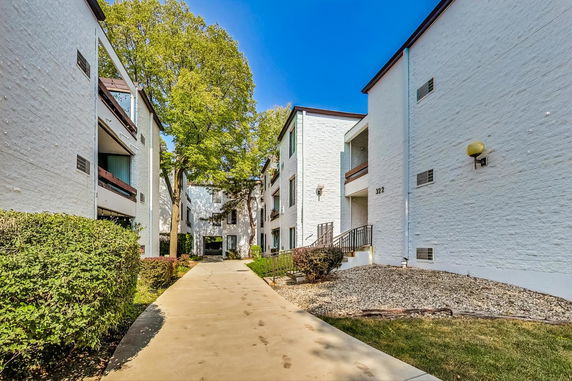 Front view of a multi-story apartment building with white brick exterior and balconies.