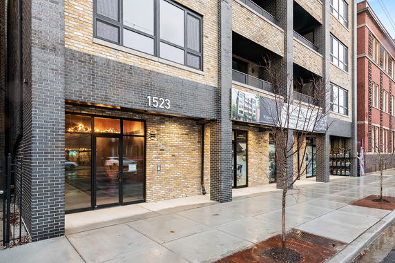 Front view of a multi-story brick building with large windows and an entrance labeled 1523.