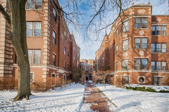 Front view of a multi-story brick apartment building with symmetrical design and large windows.