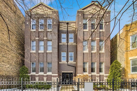Front view of a multi-story brick apartment building with symmetrical windows.