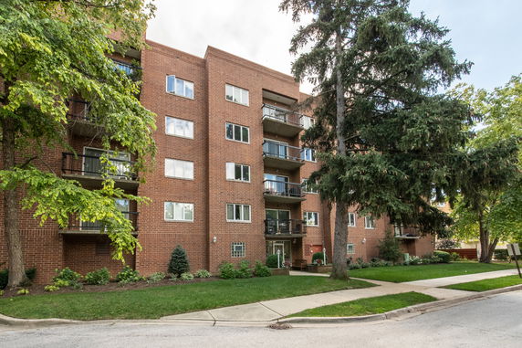 Front view of a multi-story brick apartment building with balconies.