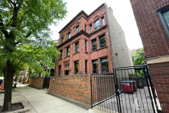 Front view of a three-story brick building with a gated entrance.