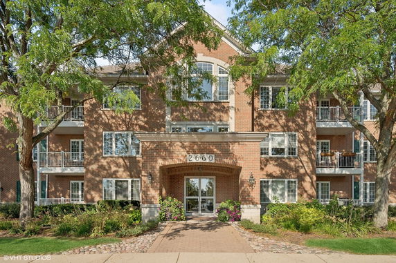 Front view of a multi-story brick building with balconies and large windows.