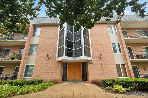 Front view of a multi-story residential building with brick facade and balconies.