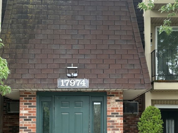 Front view of a house with a brick exterior and a large brown shingle roof.